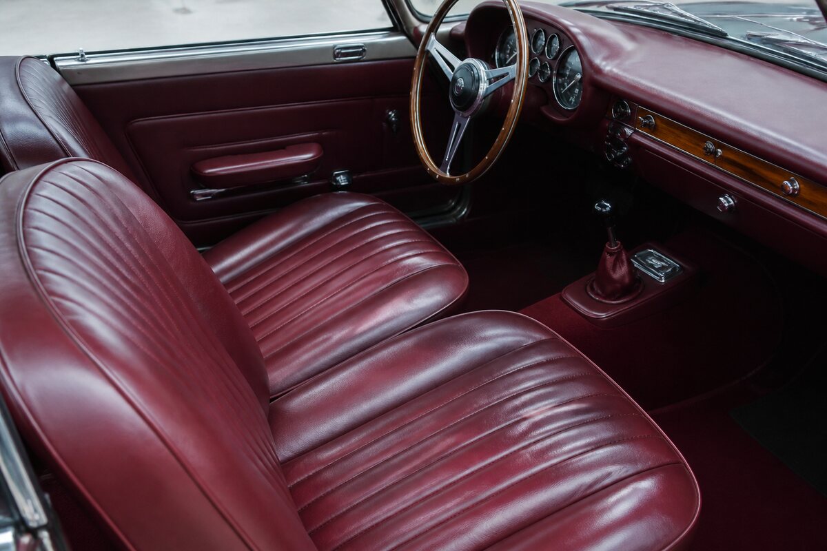 Burgundy leather classic car seat and dashboard edge in a restoration bay